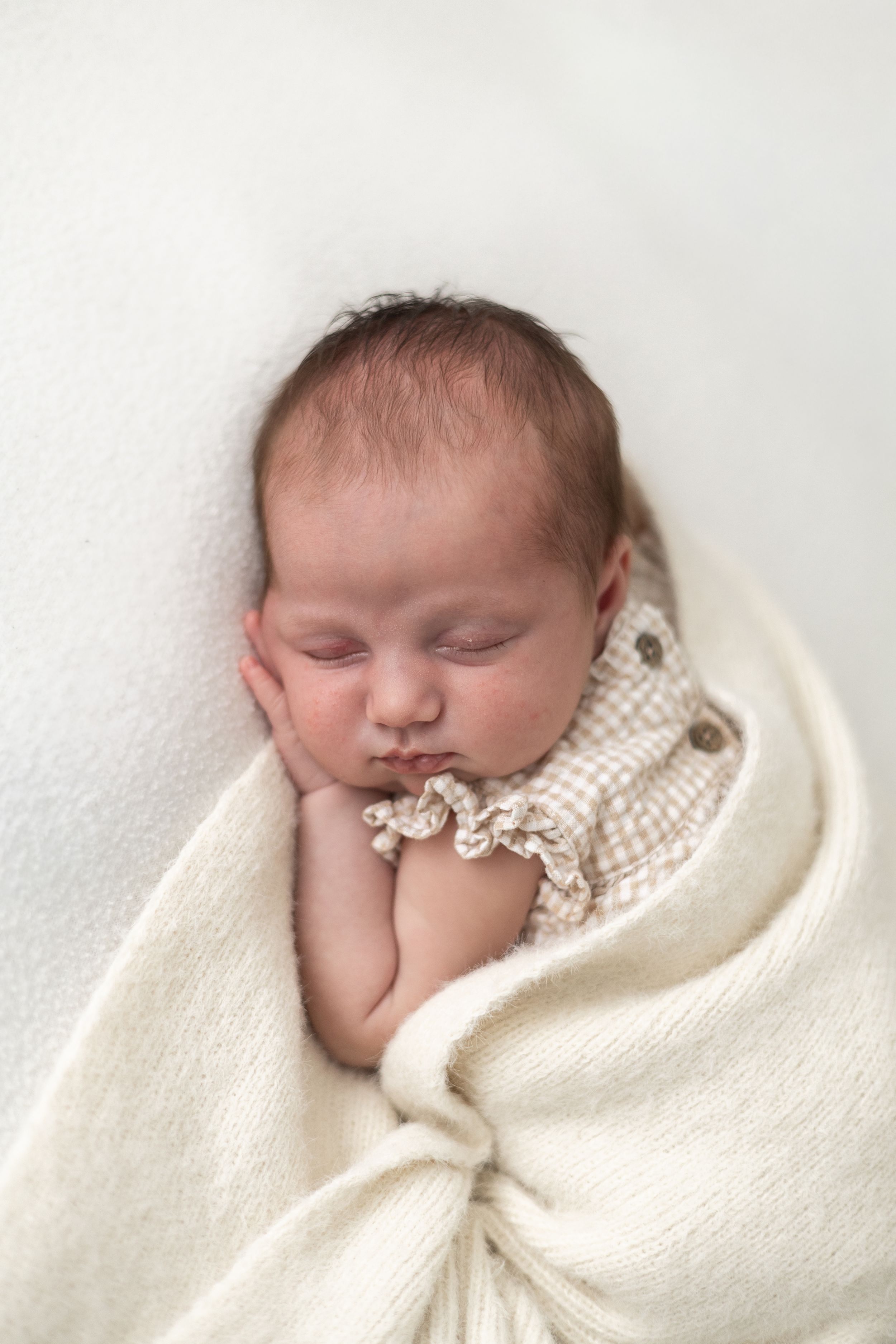 Peaceful newborn baby sleeping wrapped in a soft cream knit blanket Nottingham newborn photography portrait.