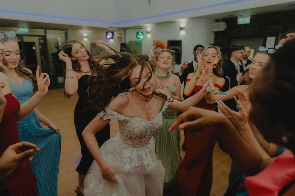 Bride dancing joyfully with guests at wedding reception party.