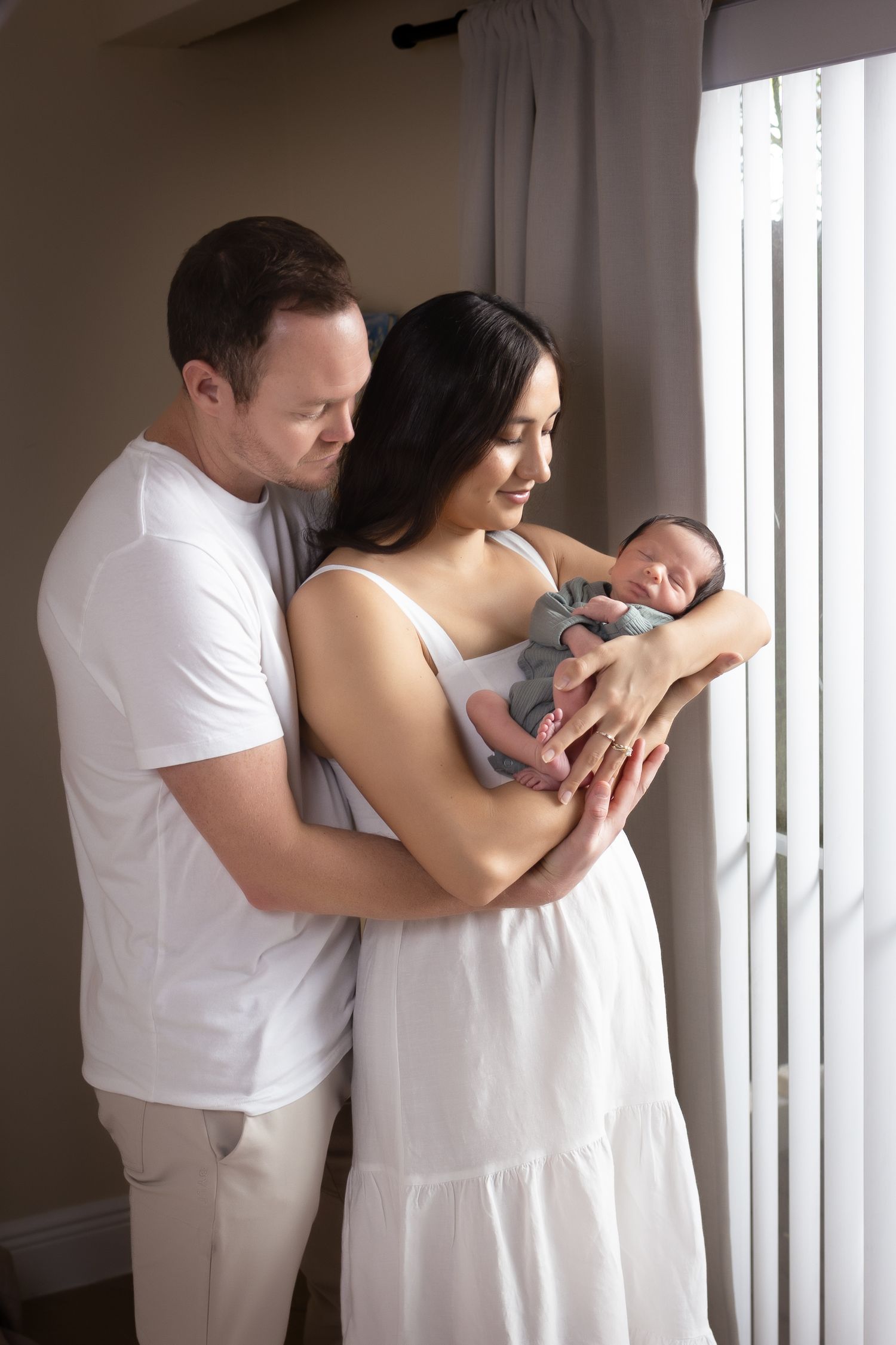 Sleeping newborn wrapped in brown fabric lying in a white furry basket during a photoshoot.