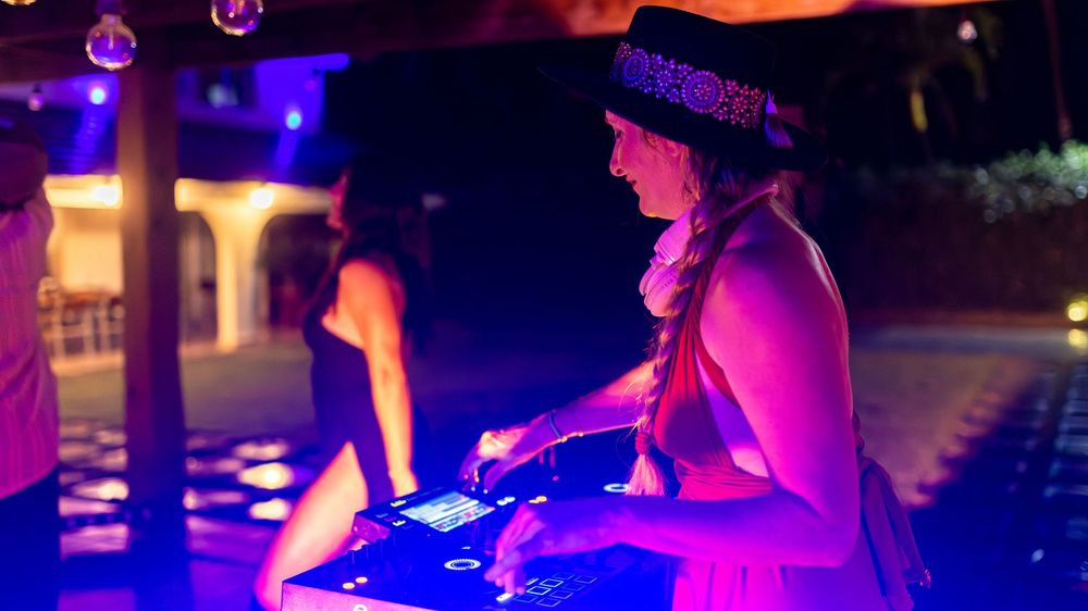 Silhouettes of people dancing at a nightclub illuminated by vibrant purple and blue lighting effects.