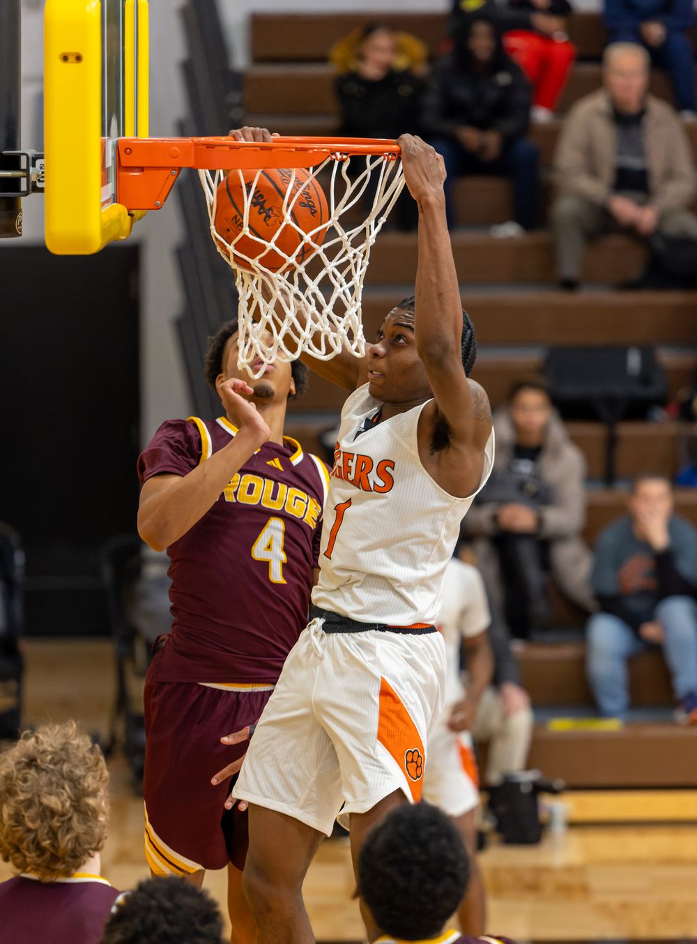 Basketball player in white jersey jumps to score against maroon-uniformed defender during intense game action.