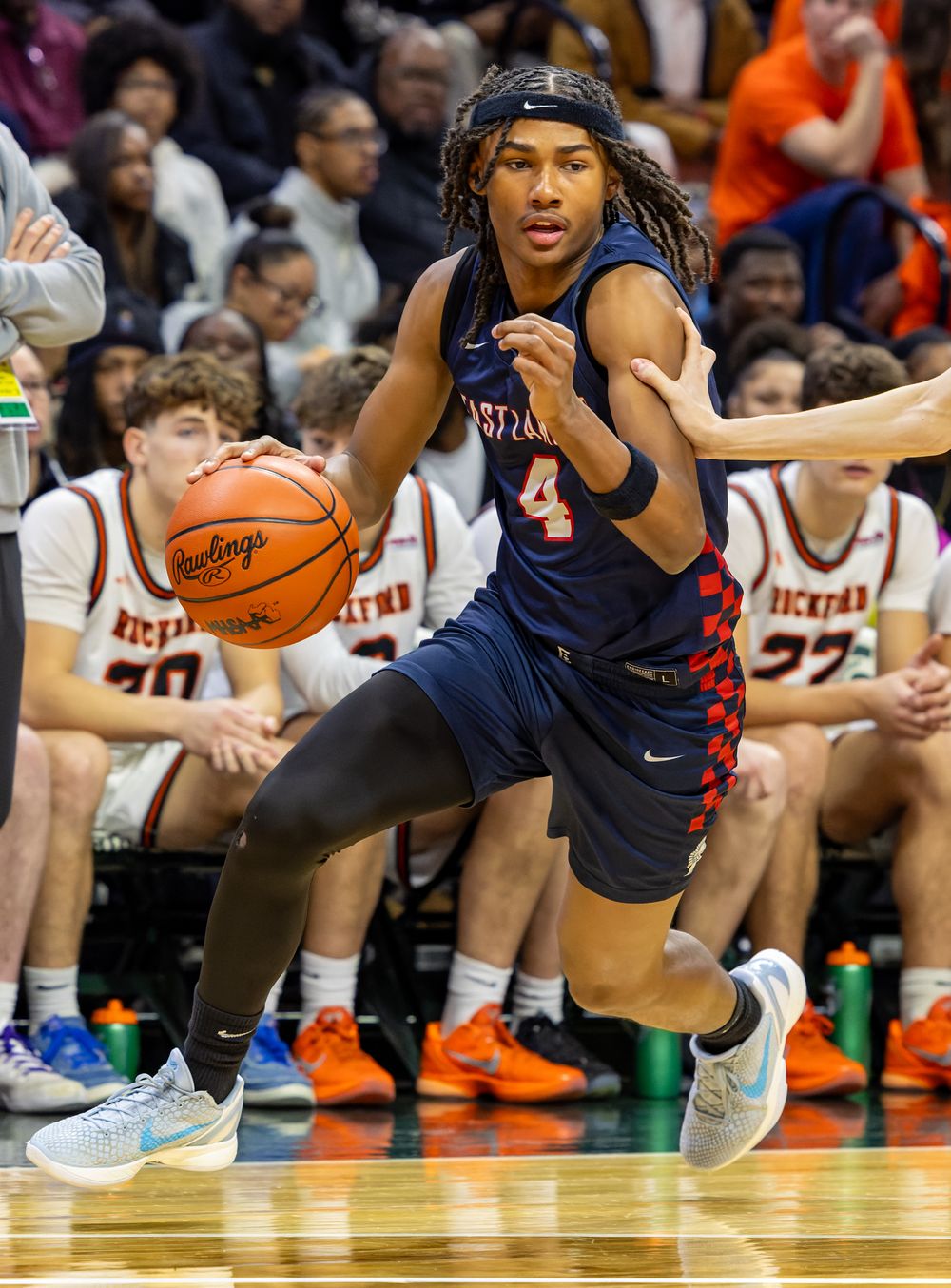 A basketball player wearing a blue jersey is dribbling the ball down the court during a game.