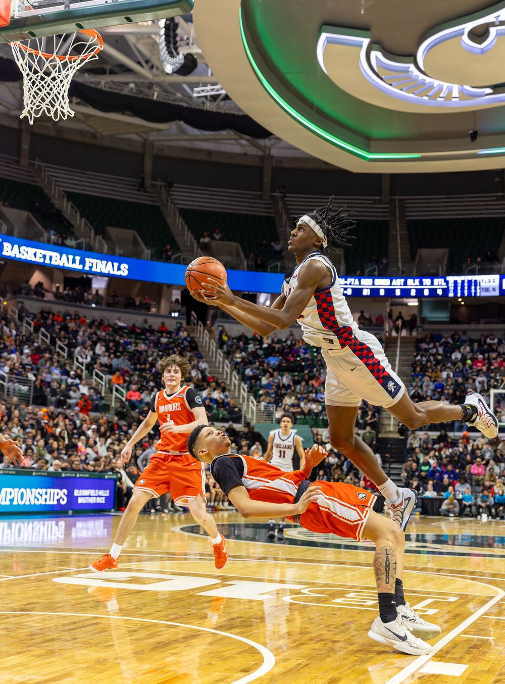 A basketball player drives to the hoop during a basketball game played in an indoor arena.