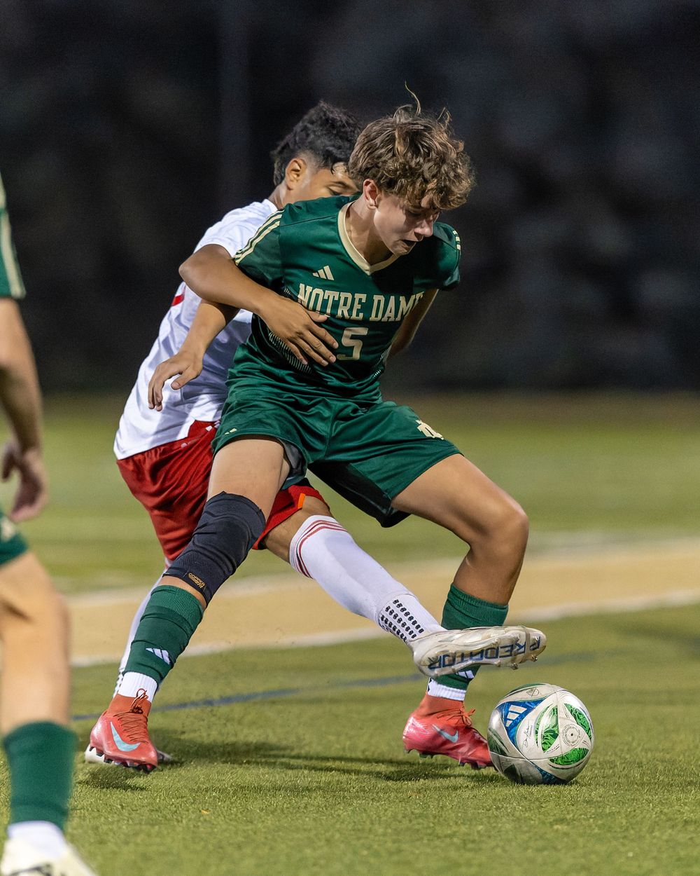 Soccer players battle for possession of the ball during a competitive match on the field.