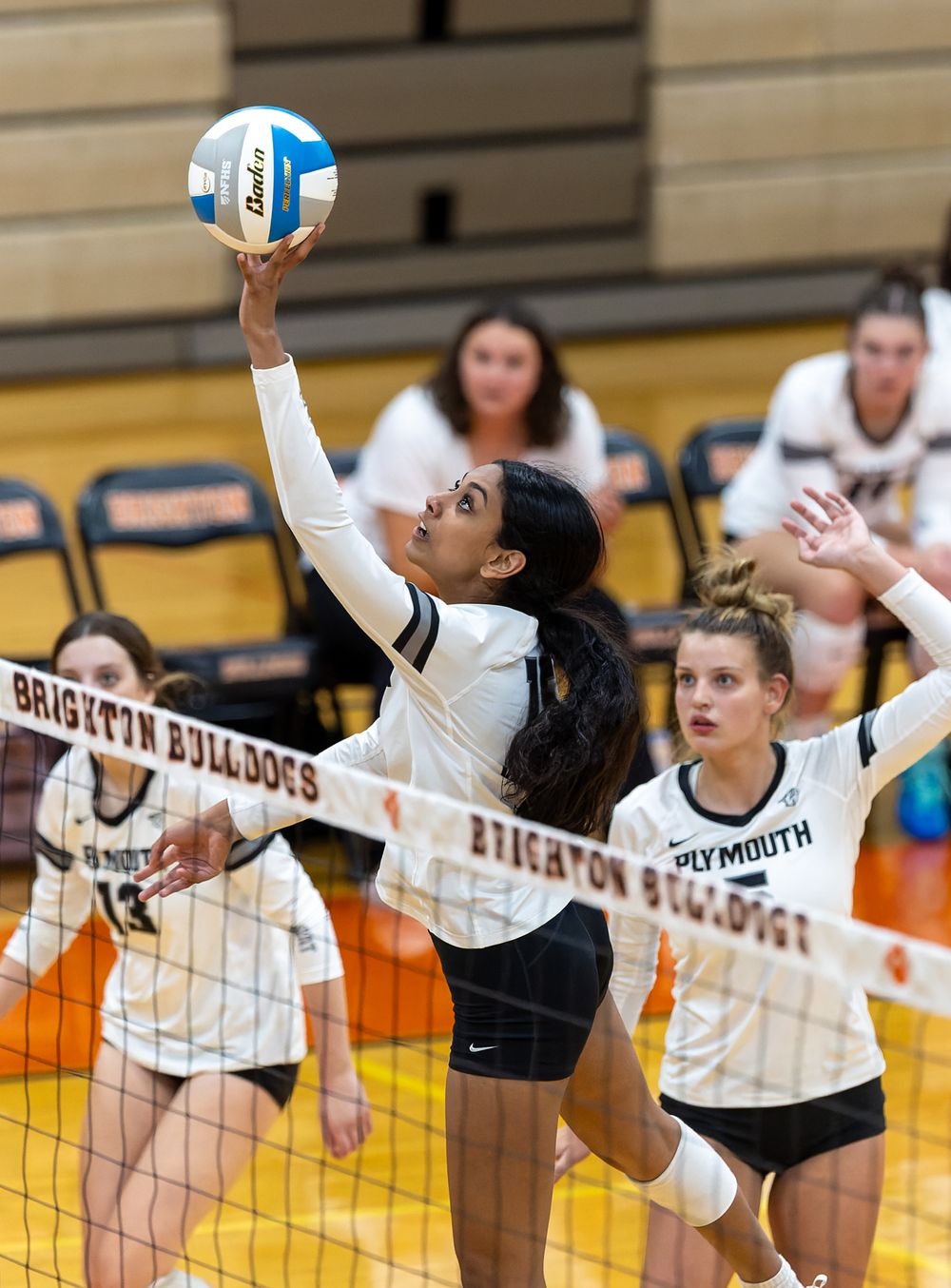 Multiple action shots show volleyball players jumping and hitting during a competitive game.