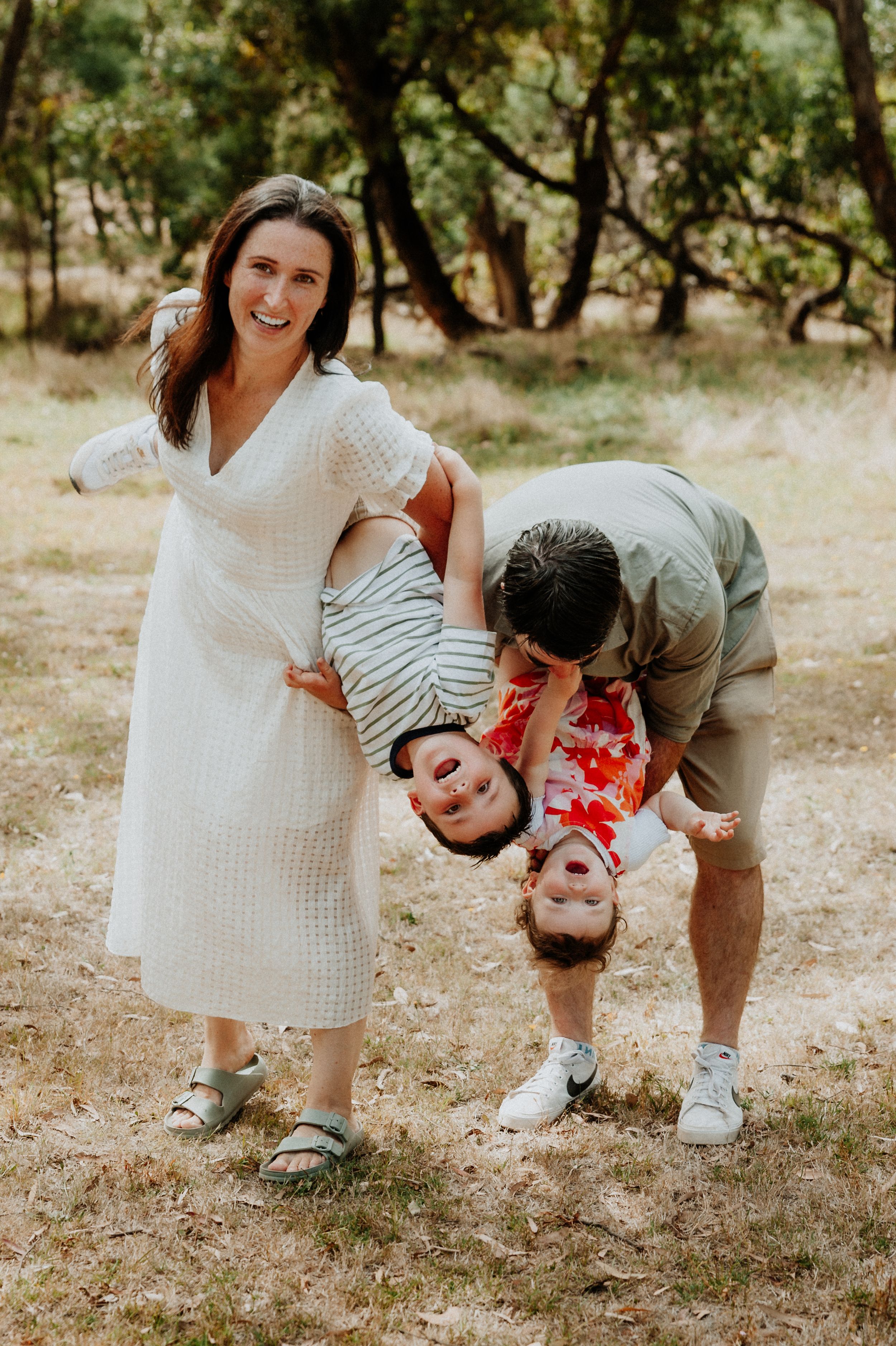 A playful family photo with parents holding a giggling child upside down in a wooded setting.
Altona Family Photographer Melbourne