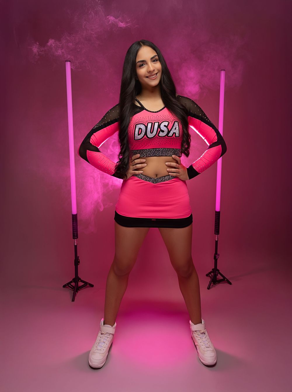 Athletic figure in pink and black sportswear poses against pink backdrop with vertical lighting elements.