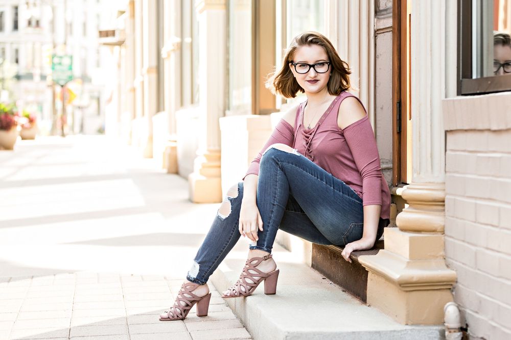 Casual lifestyle portrait on urban steps featuring denim and pink sweater outfit. Grand Rapids Photographer