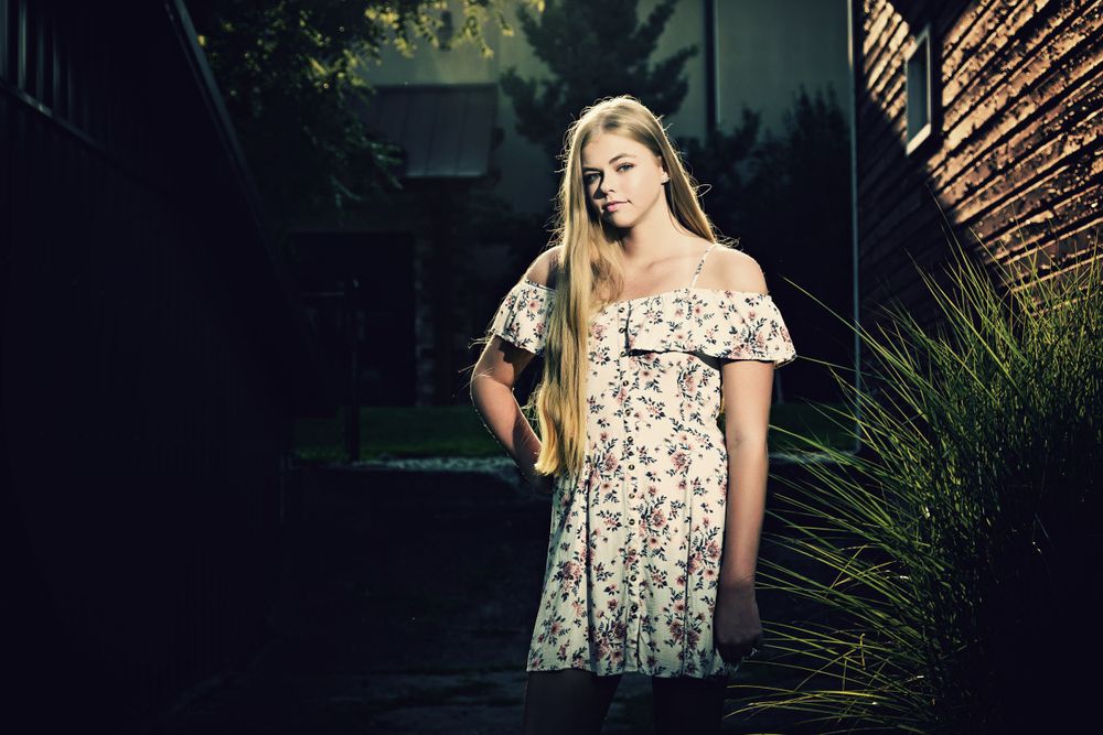 Dramatic lighting portrait in floral dress against dark natural background. Grand Rapids Photographer