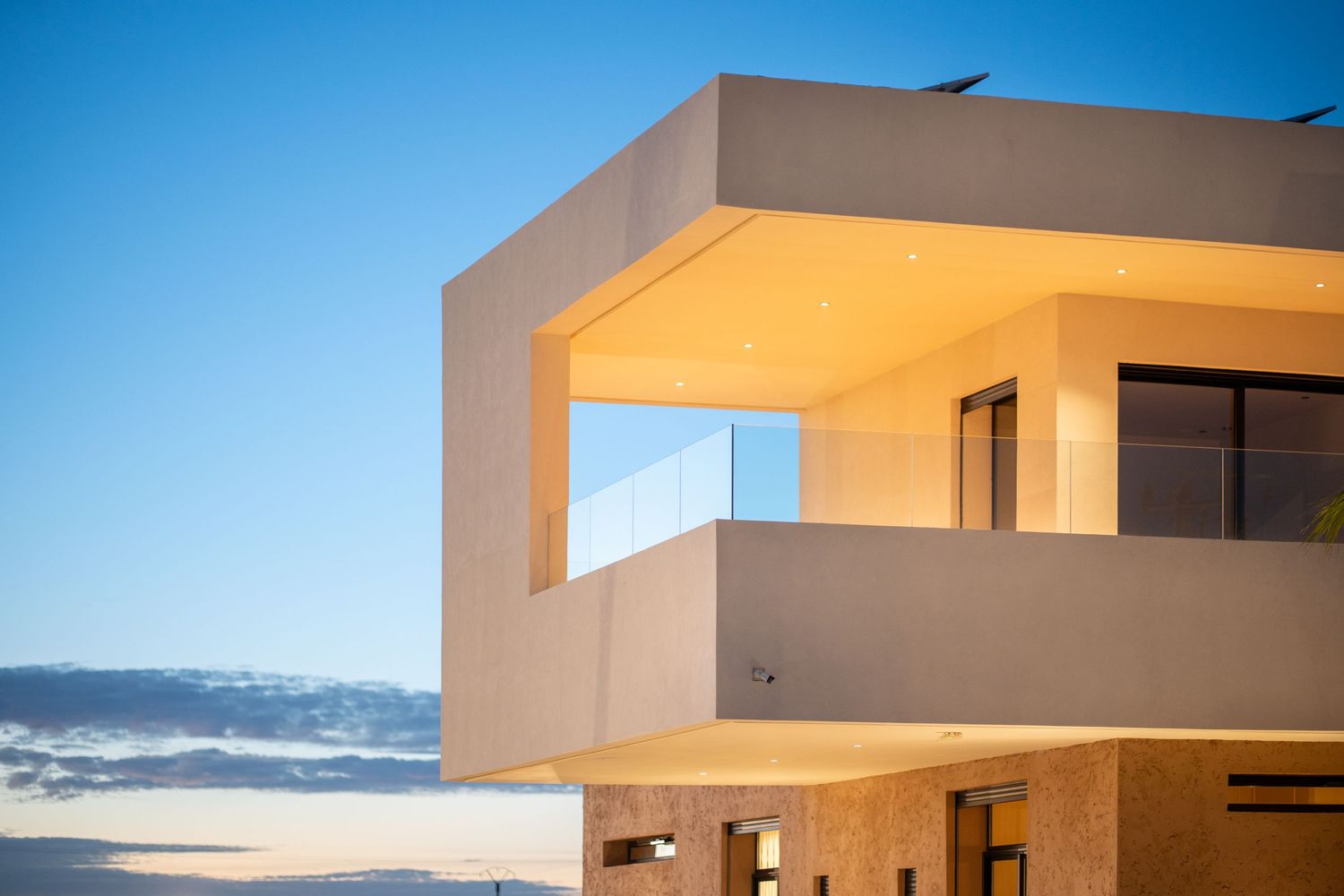Modern angular beige building exterior with geometric shapes illuminated at sunset.