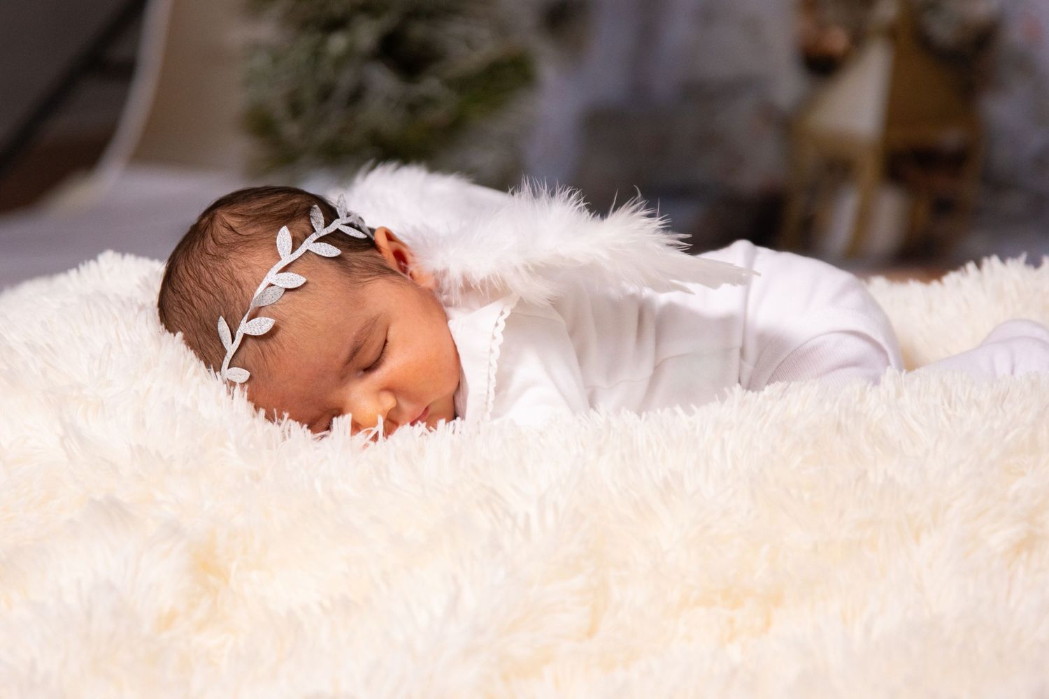 Sleeping newborn lying on soft white fur blanket.