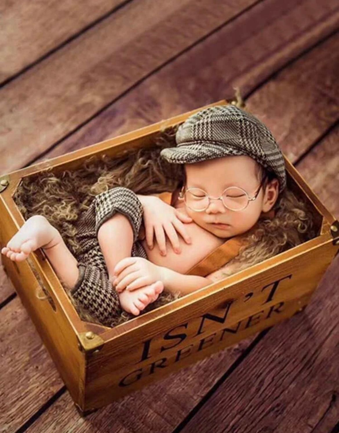 Vintage style newborn photography in wooden crate with newsboy cap.
