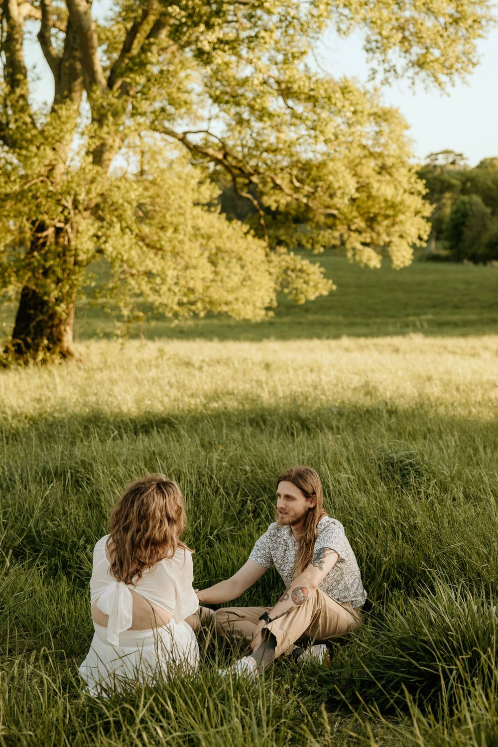 Two people sitting together in a sunlit field having a peaceful moment.