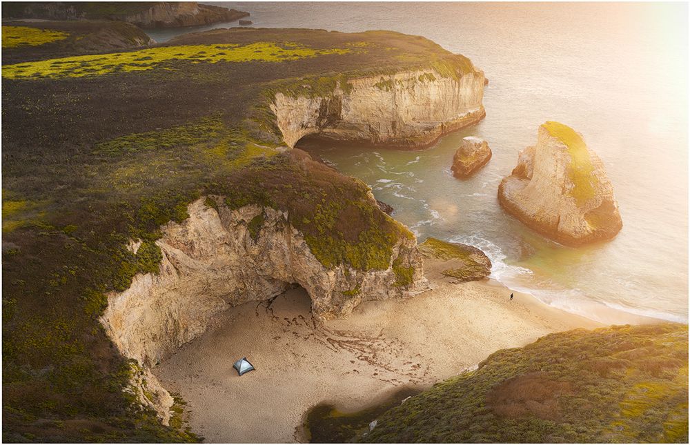 Coastal limestone cliffs and beach cove during golden hour sunset.