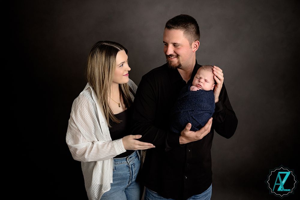 Candid family moment with parents and newborn in studio setting.
