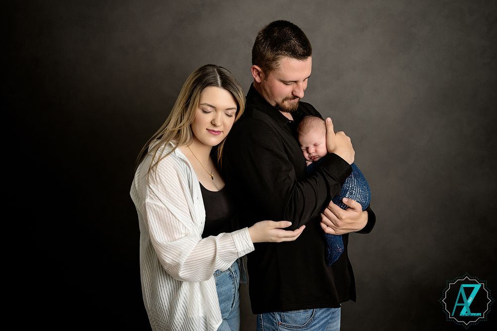 Intimate studio portrait of parents gazing lovingly at their newborn.