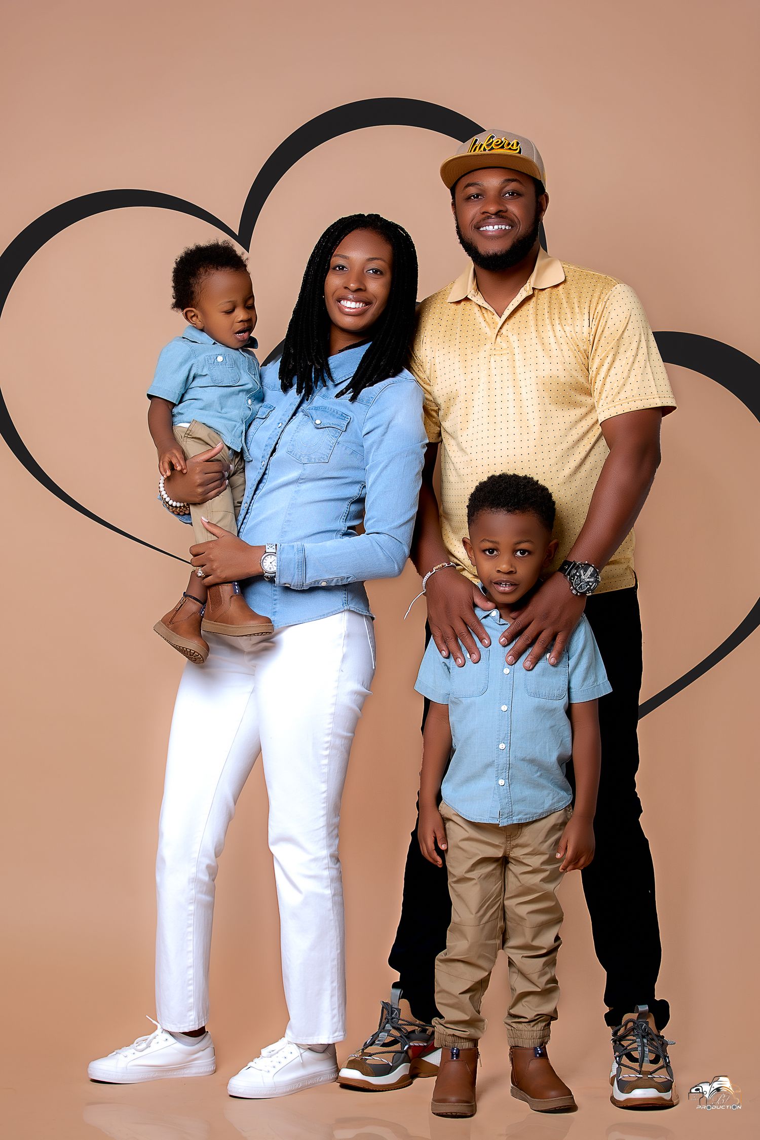 A family of four poses together against a brown background with a heart design.