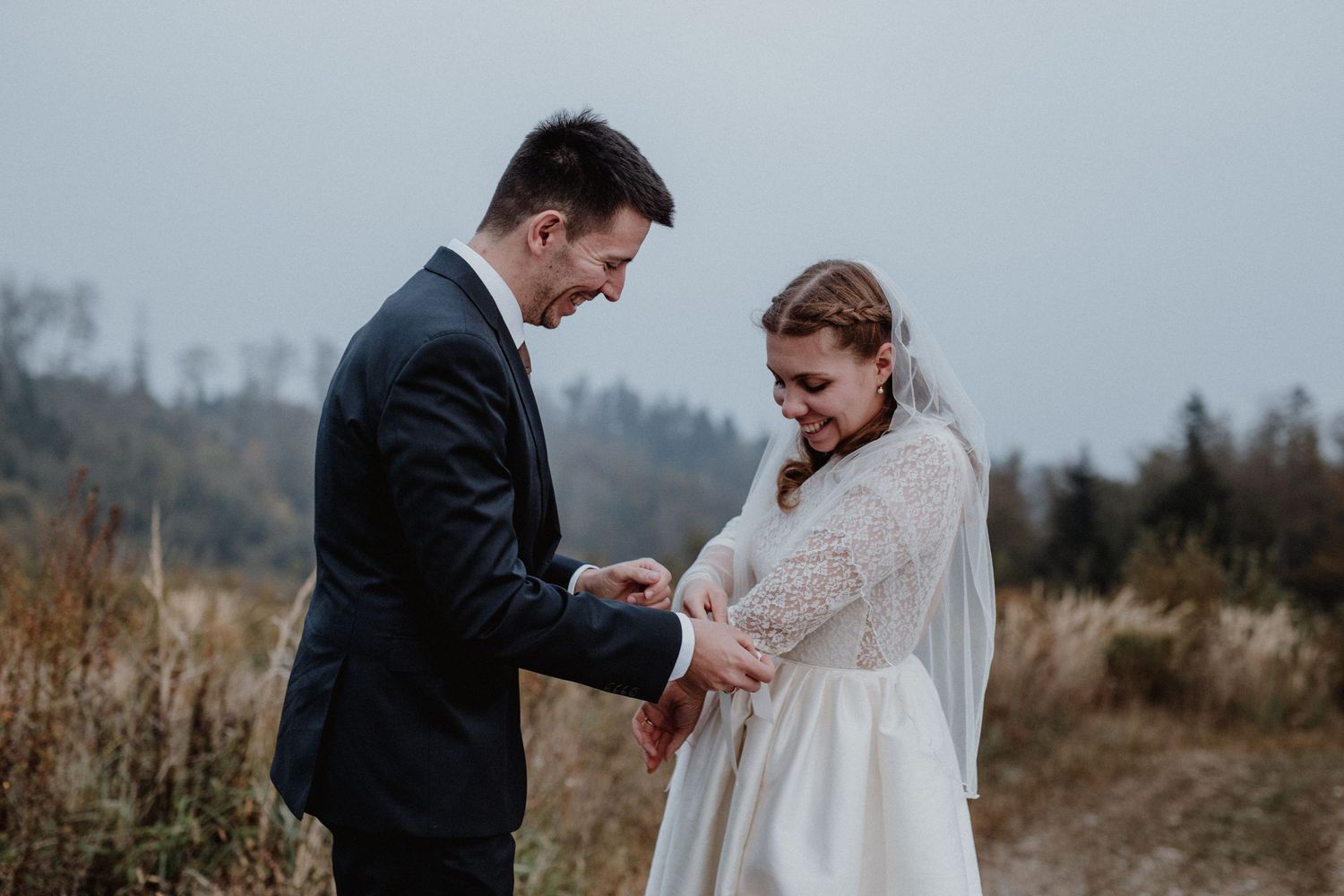 A couple in wedding attire shares an intimate moment in a misty mountain landscape.