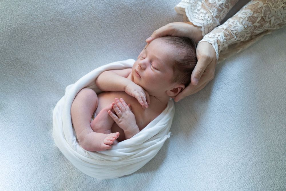 fotografia newborn a domicilio, neonata che dorme, neonata con occhi chiusi, foto a casa Peschiera Borromeo, a Milano, fasciatura con wrap