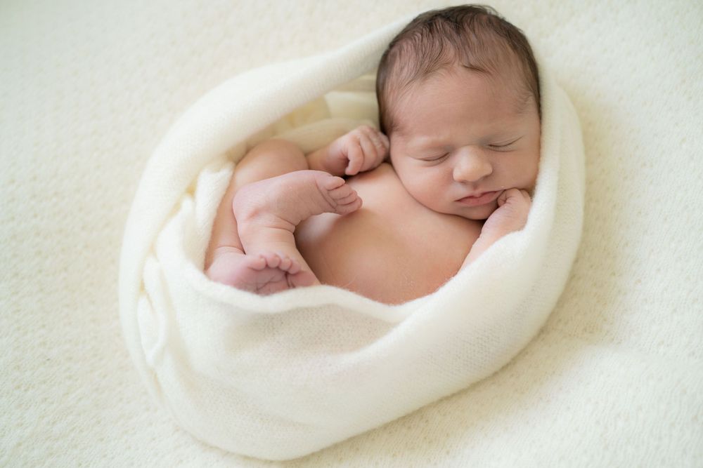 fotografia newborn a domicilio, neonata , neonata fasciata in un wrap di lana fatto a mano, foto ricordi a casa Peschiera Borromeo