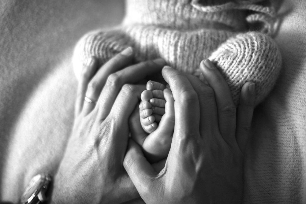 mani papà intorno alle mani di suo figlio neonato