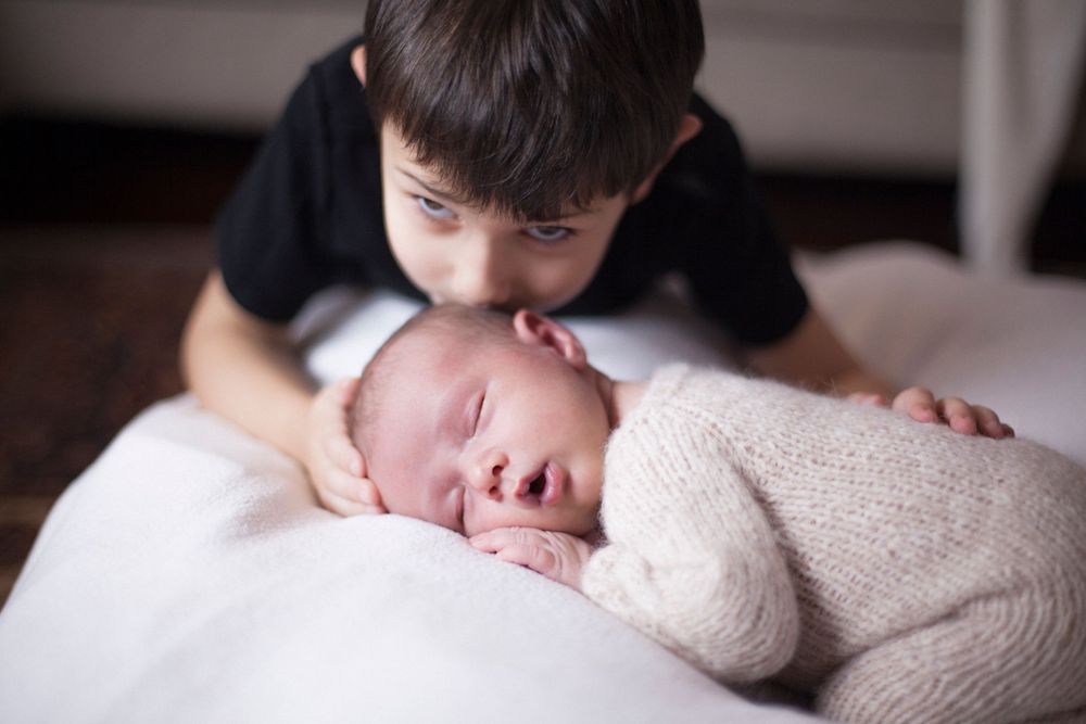 fratelli, fotografia famiglia a domicilio, fratello con neonato, bacio sulla testa, fotografa famiglia a domicilio a Peschiera Borromeo