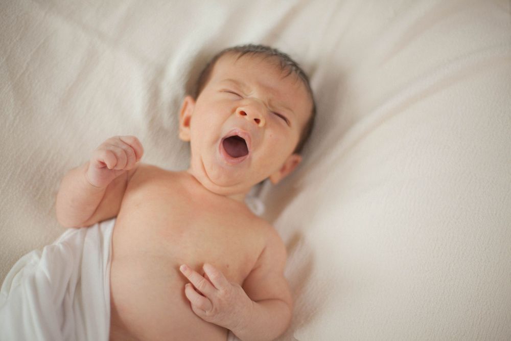 fotografia newborn a domicilio, neonato che sbadiglia, fotografa a domicilio a Peschiera Borromeo, a Milano, bean bag wrap cotone