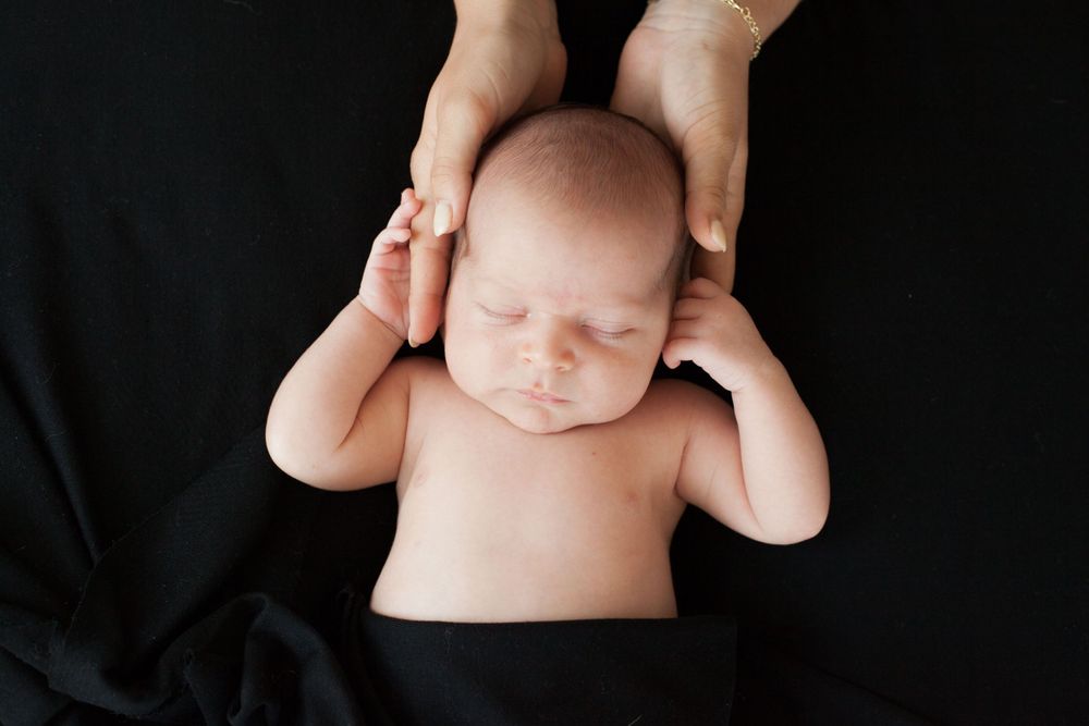 sessione neonata sfondo telo nero, neonata, abbraccio mamma, fotografa newborn a domicilio Milano, mamma e figlia, affetto, amore, carezza