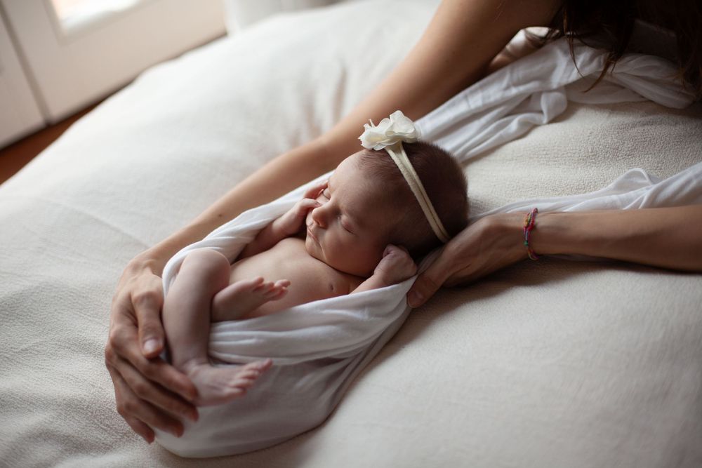 neonata posata con un telo bianco e una fascetta bianca sulla testa