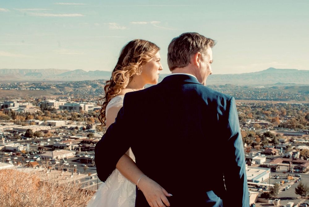 Bride and groom standing together overlooking scenic city valley landscape on their wedding day.