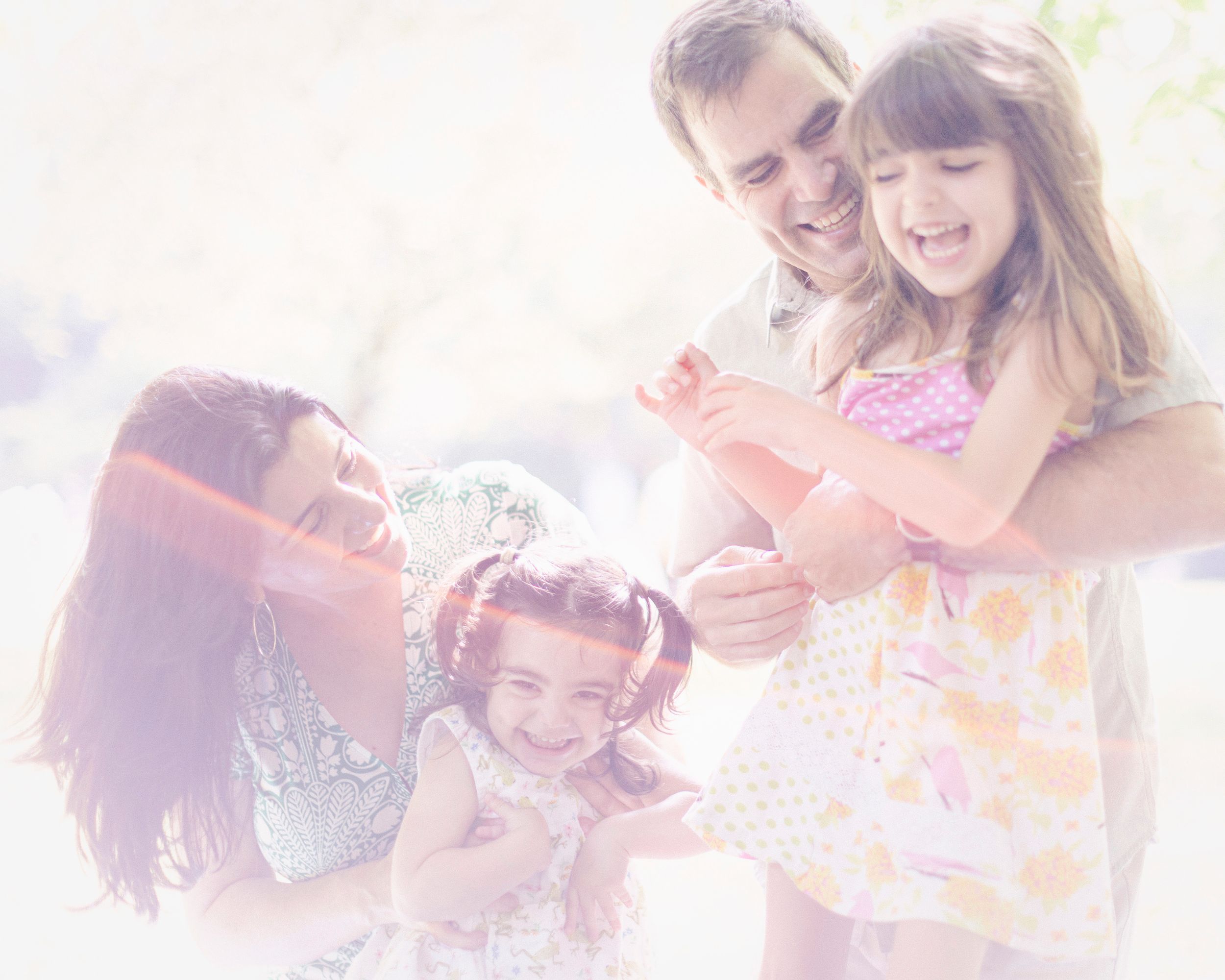 A dreamy, light-filled family photo capturing playful moments and genuine laughter.