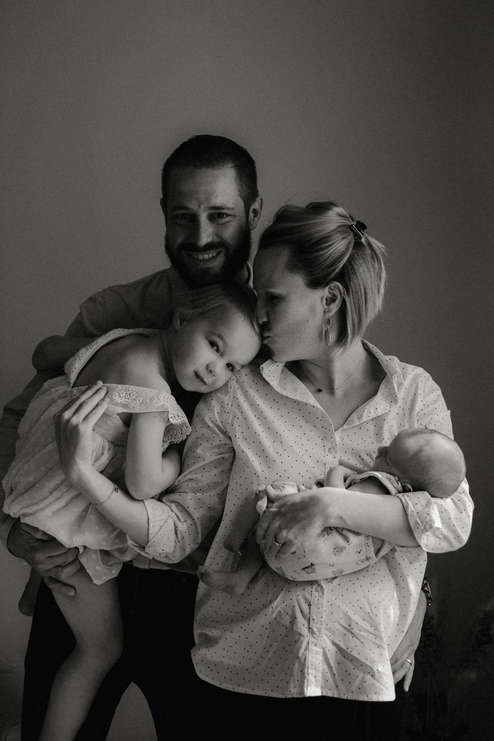 Intimate black and white family portrait showing tender moment with children.