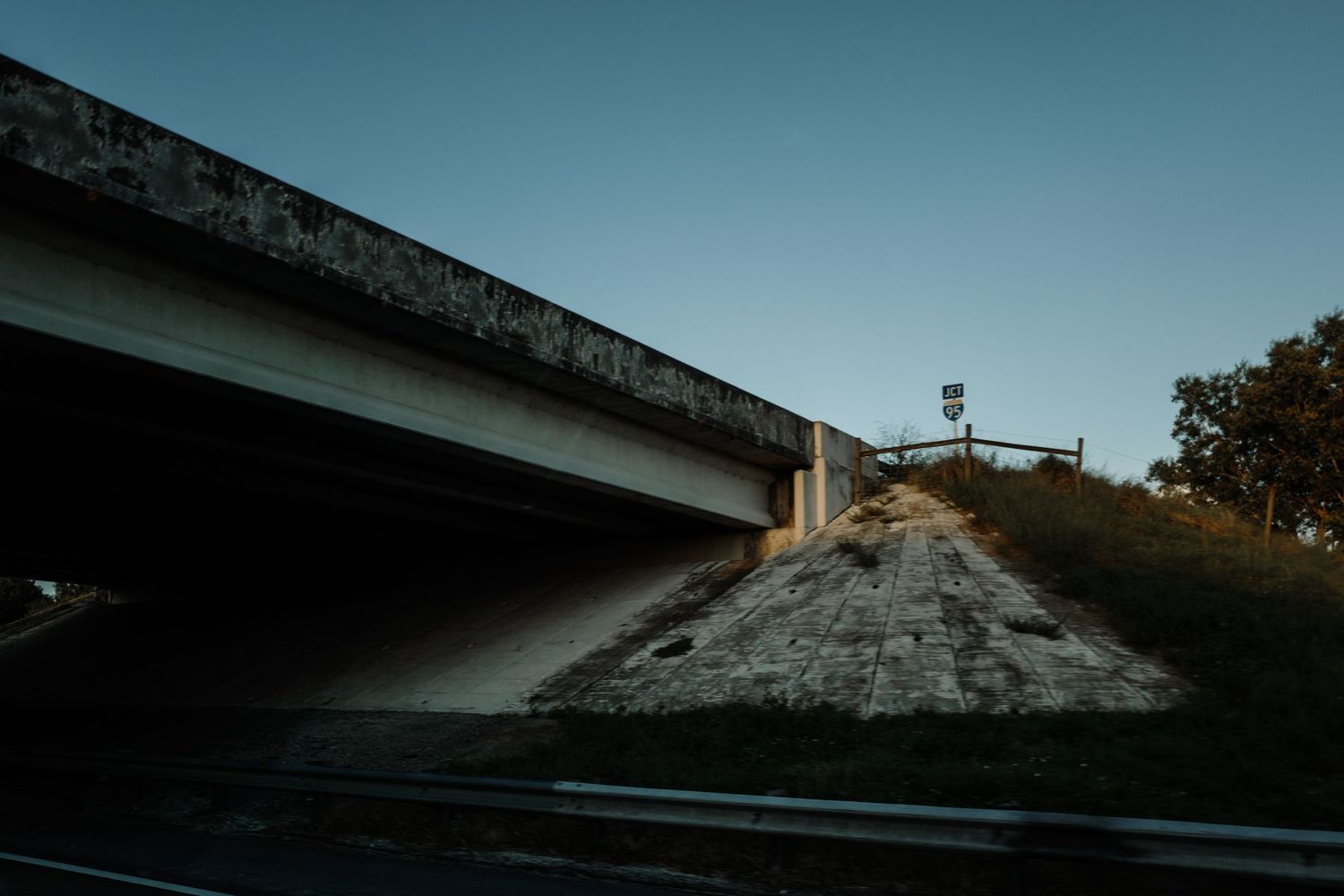 Low angle view of underpass and embankment against clear blue sky.