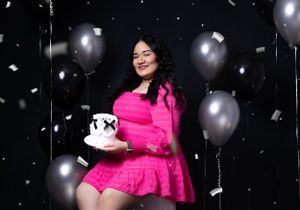 Celebratory scene with silver balloons and confetti featuring bright pink dress and decorative cake.