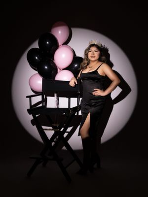 Glamour portrait with black and pink balloons against spotlit background.