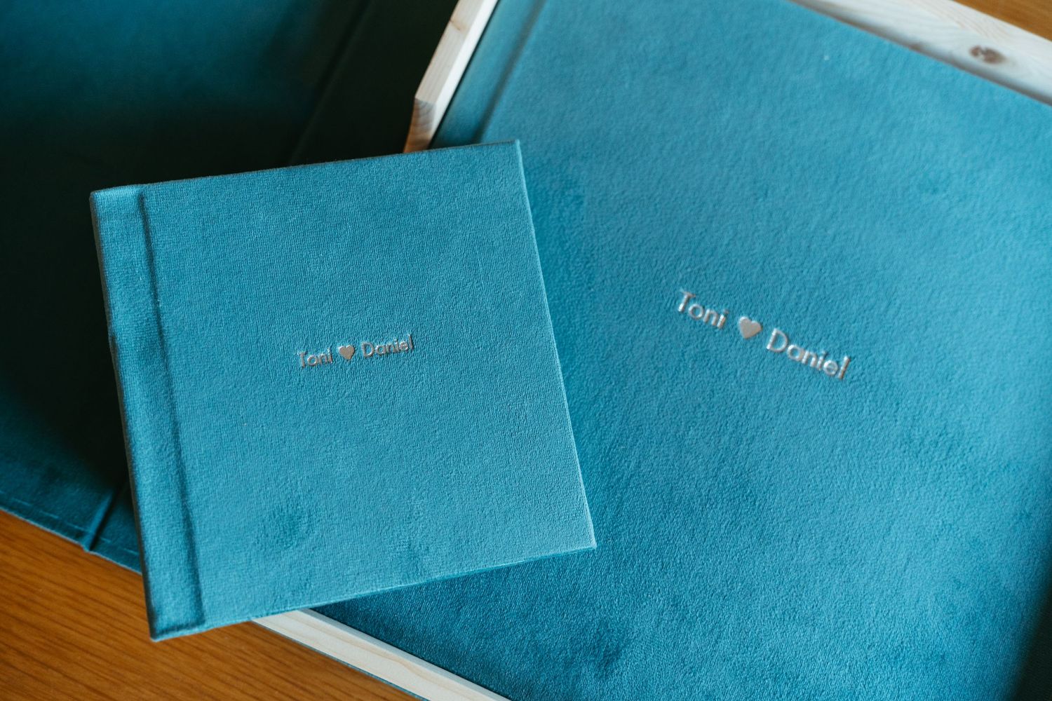 Row of teal blue wedding invitation envelopes on wooden surface.