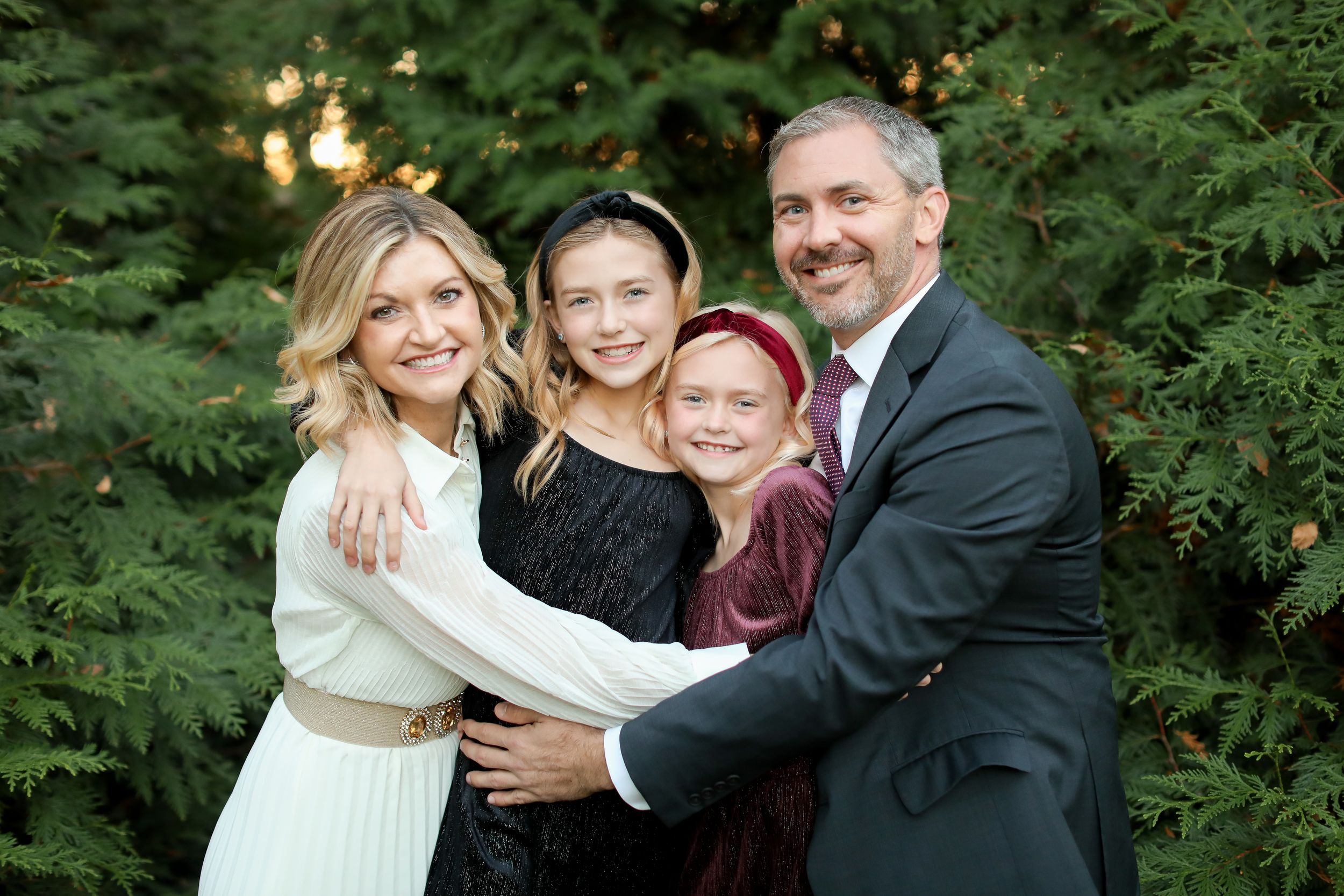 Holiday family portrait with evergreen and twinkling lights background.