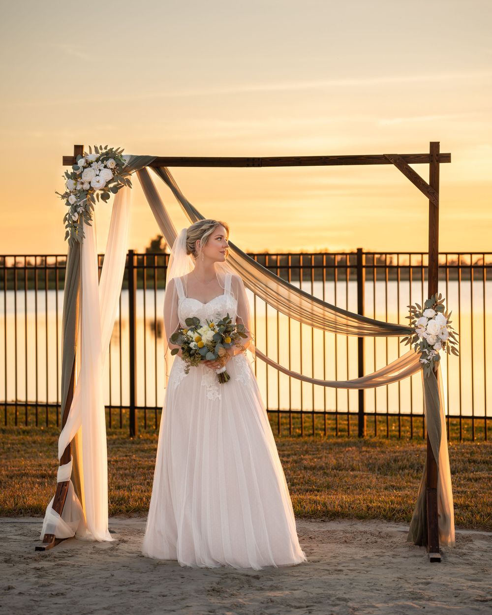 Beautiful Venice Florida wedding ceremony setup with wooden arch and floral decorations at sunset by the water.