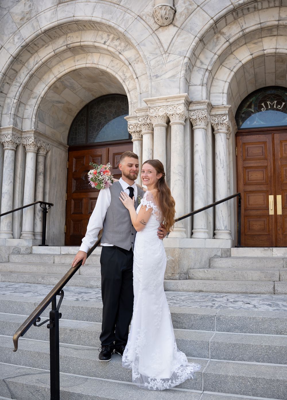 Couple shares romantic wedding moments against a stone archway at Sacred Heart Catholic Church in Tampa, Florida.