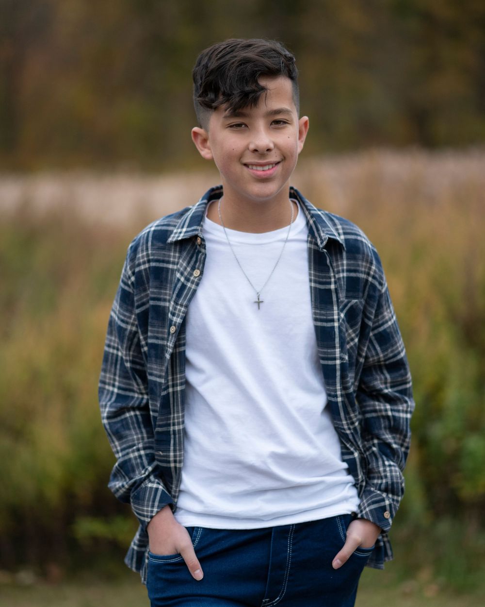 Smiling teenage boy in plaid shirt and white tee with cross necklace posing outdoors in autumn.Middletown NJ