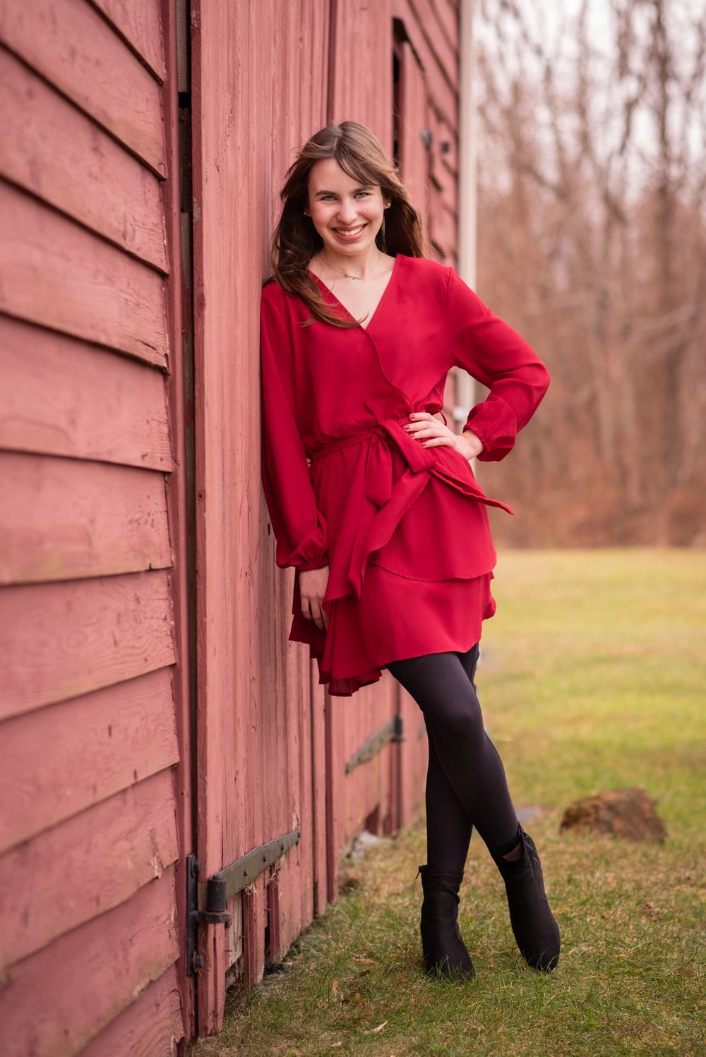 Fashionable red dress outfit styled against weathered red barn siding.Middletown NJ