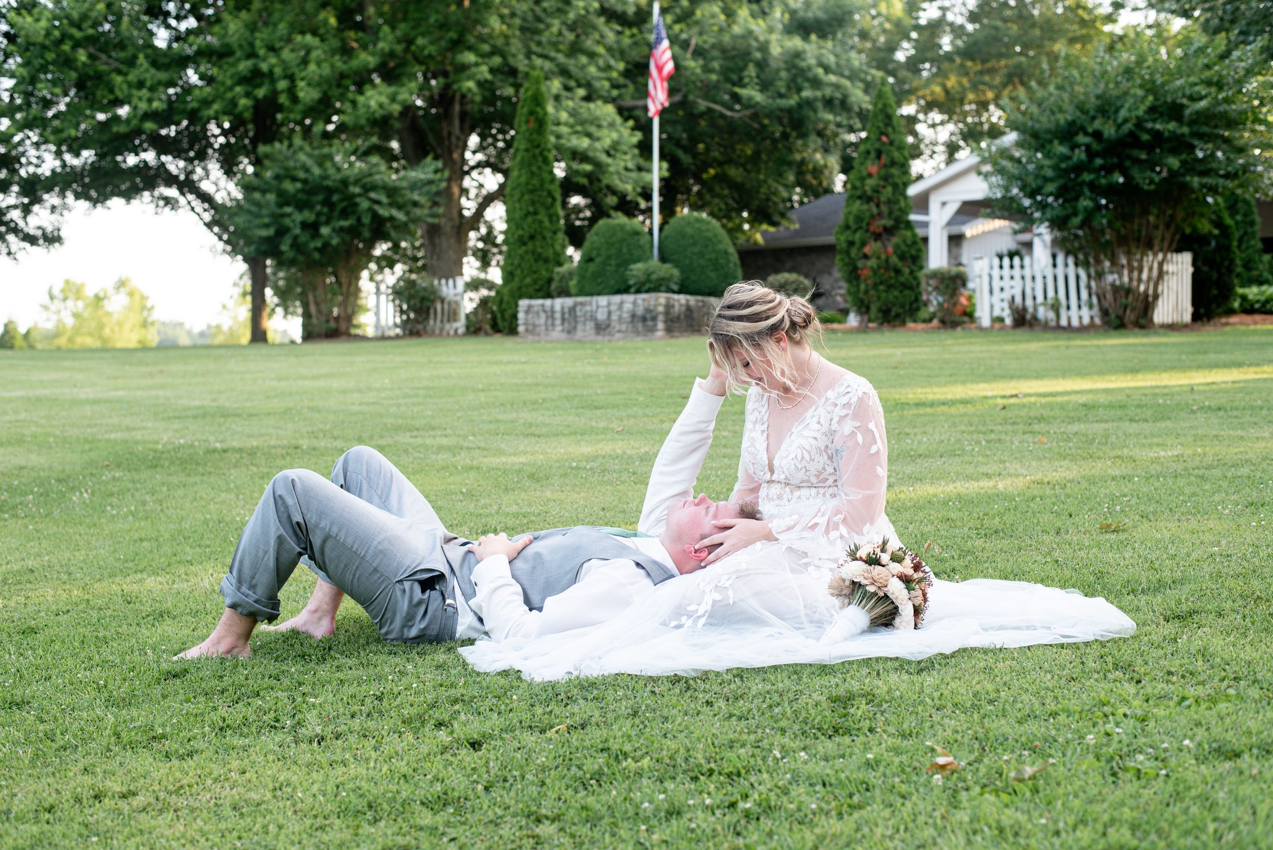 A bride and groom sitting in the grass together in Princeton, Kentucky.