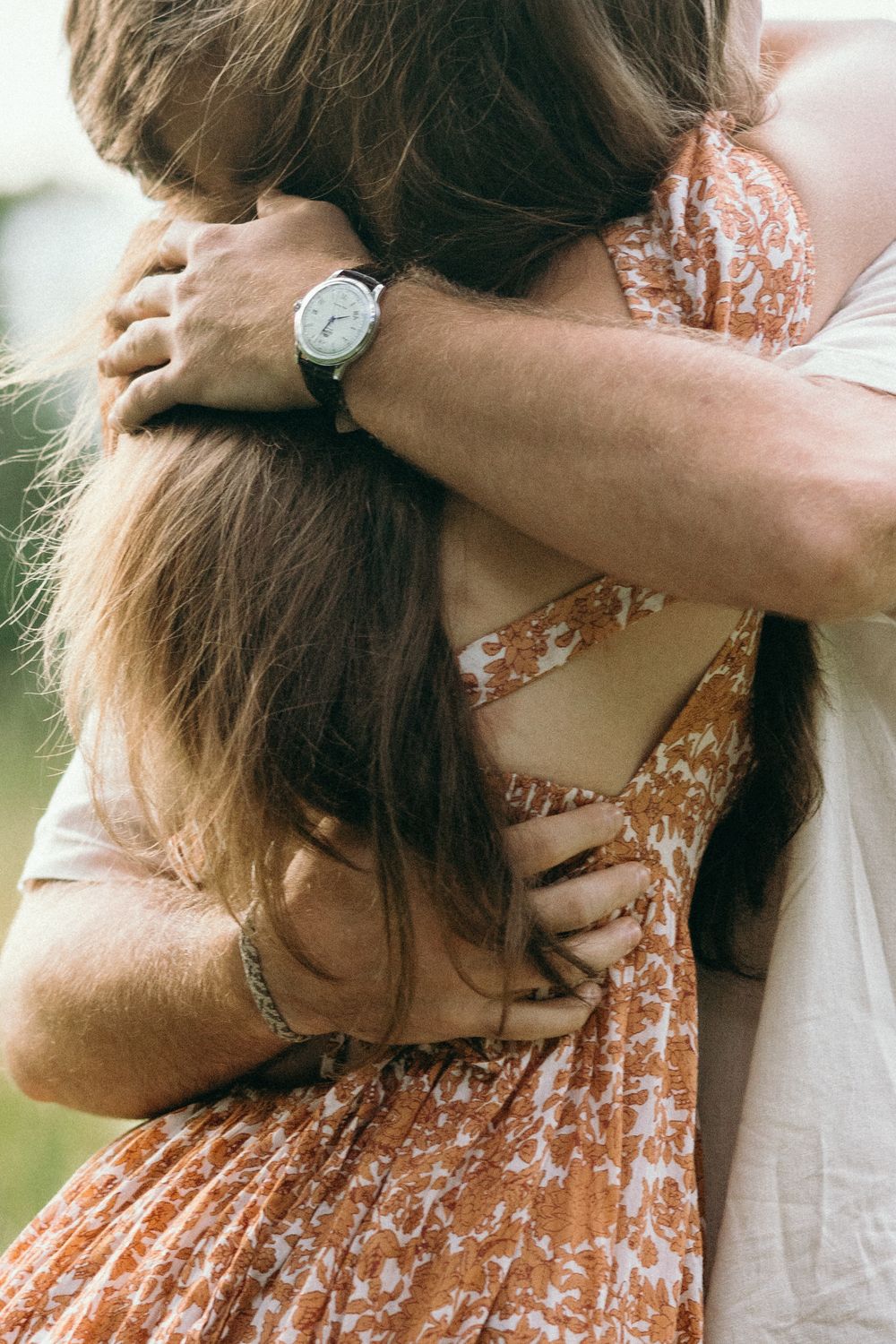 Close-up of embracing couple showing wristwatch detail and floral dress pattern. Luxury Estate Wedding Photographer in NC