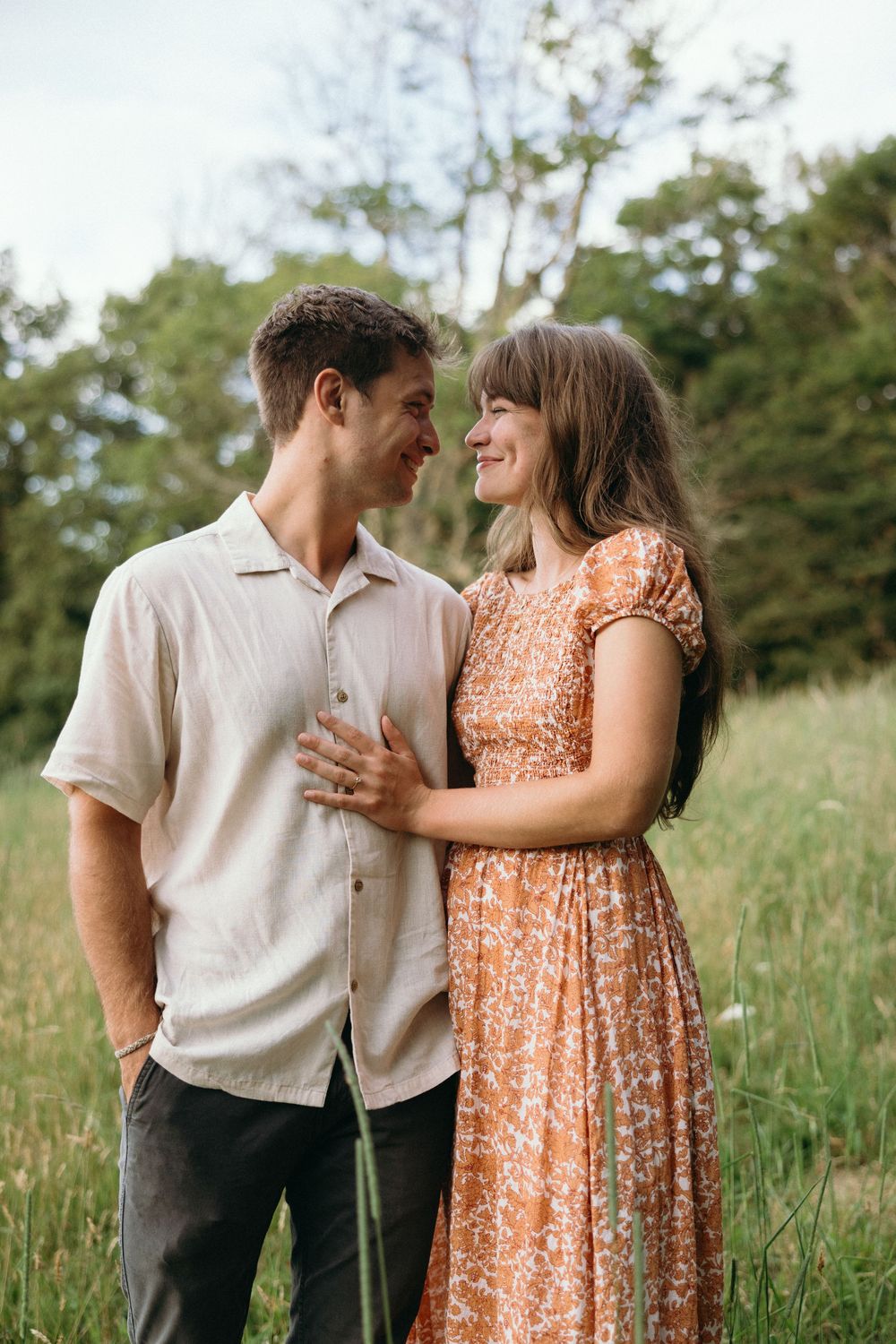Couple in casual attire sharing intimate moment in sunlit meadow. Luxury Estate Wedding Photographer in NC