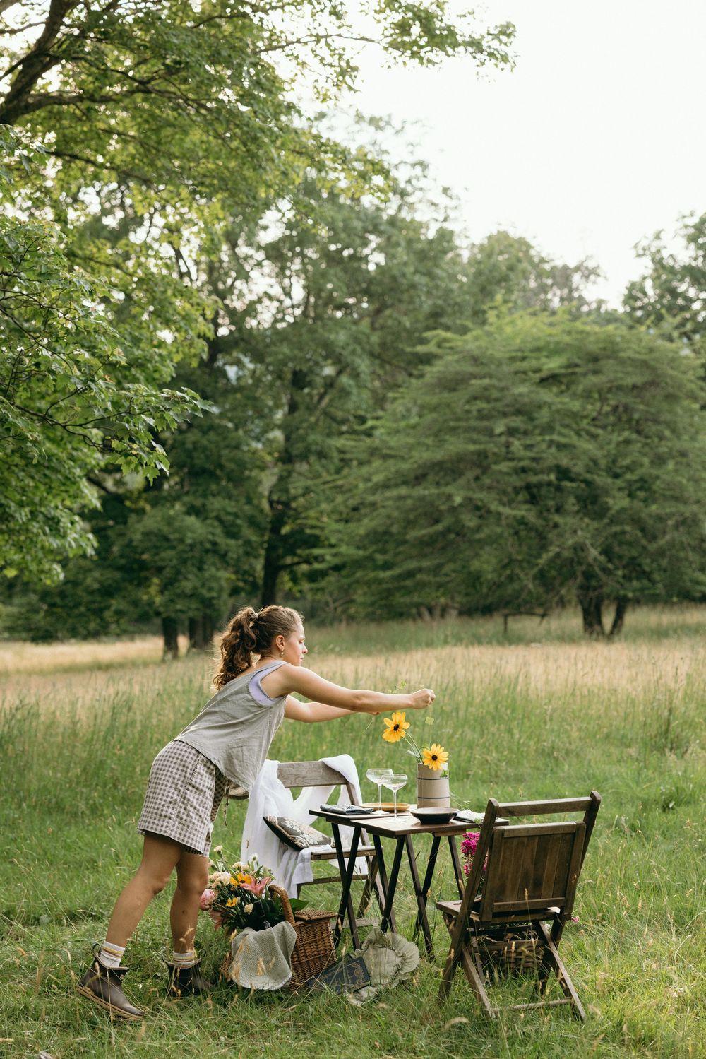 Outdoor picnic setup with folding chairs and table in a sunlit grassy field. Editorial wedding photographer for historic venue