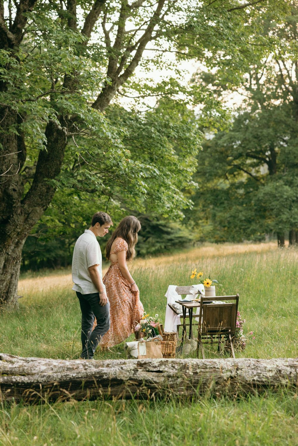 People enjoying an intimate outdoor gathering by a stone wall in a pastoral setting. Editorial wedding photographer for historic venue