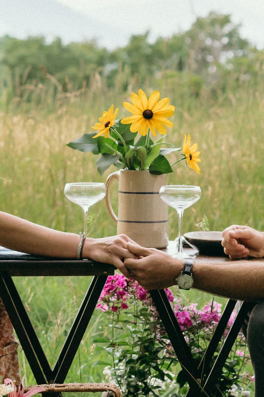 Martini glasses and sunflowers decorate a black table at an outdoor gathering. Luxury Estate Wedding Photographer in NC