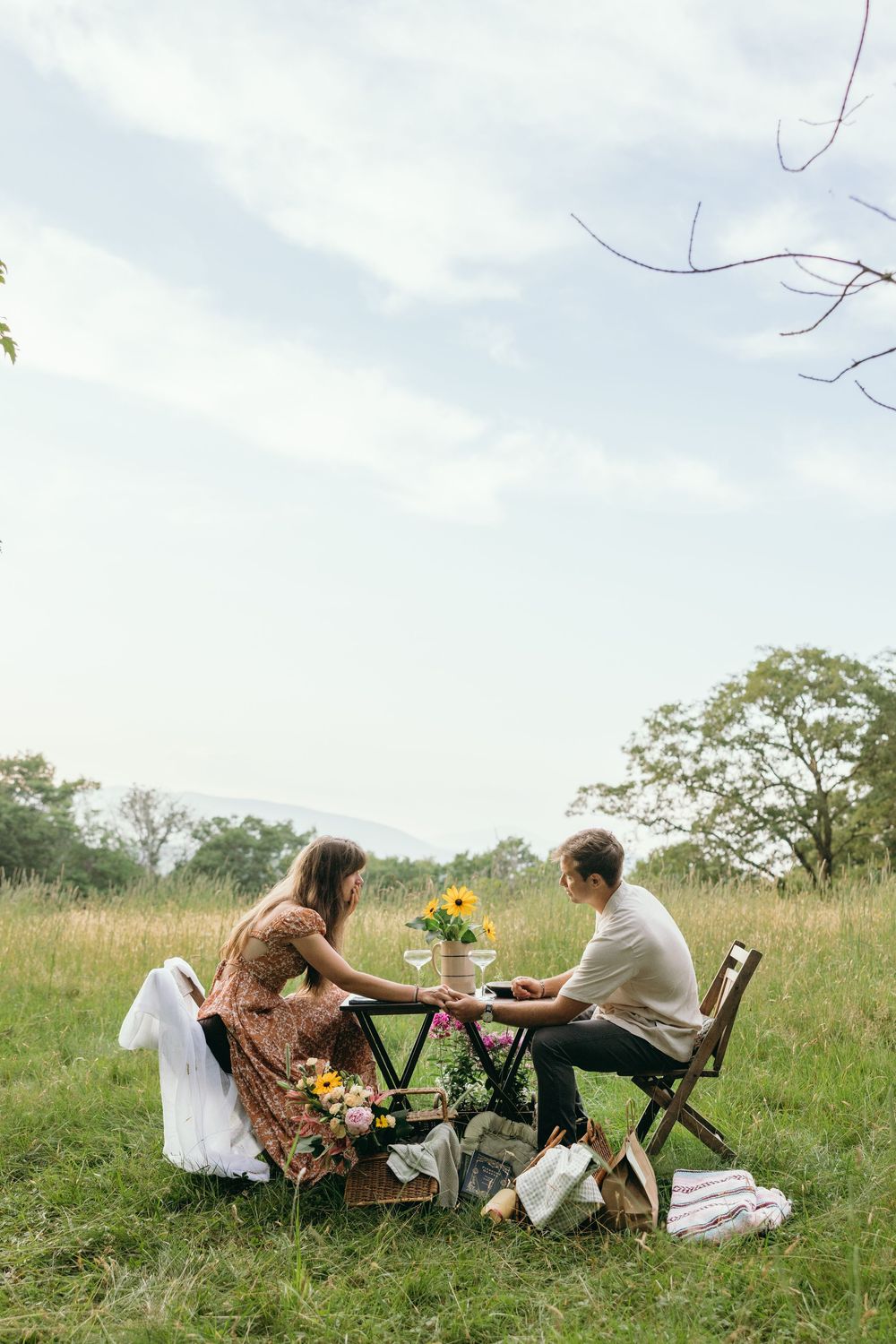 Couple enjoying an intimate outdoor picnic in a sunny meadow setting. Luxury Estate Wedding Photographer in NC