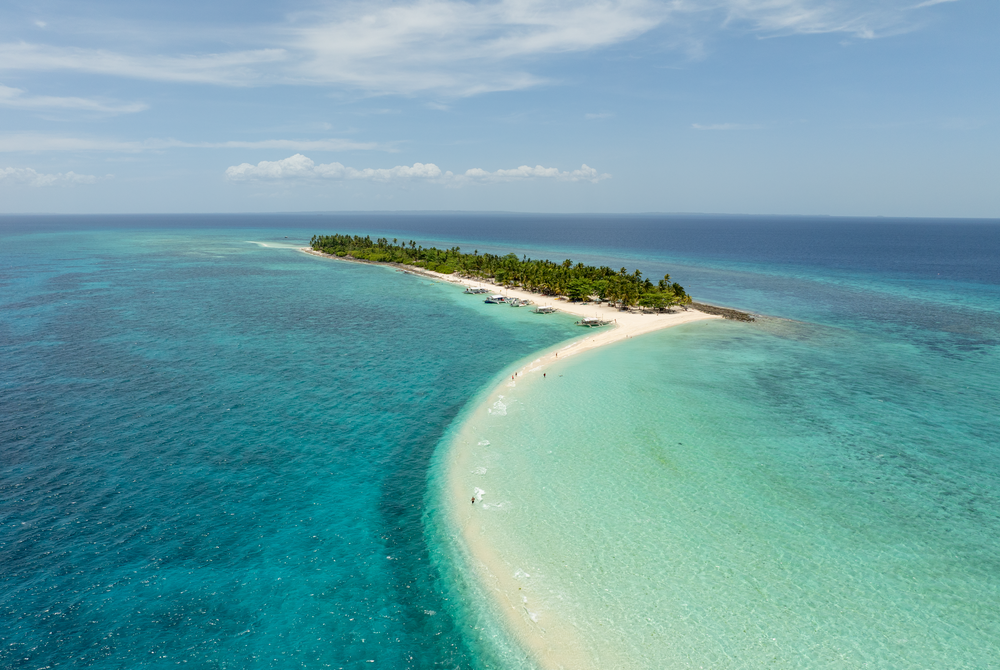 Stunning aerial view of curved tropical beach with crystal clear turquoise waters meeting white sand.