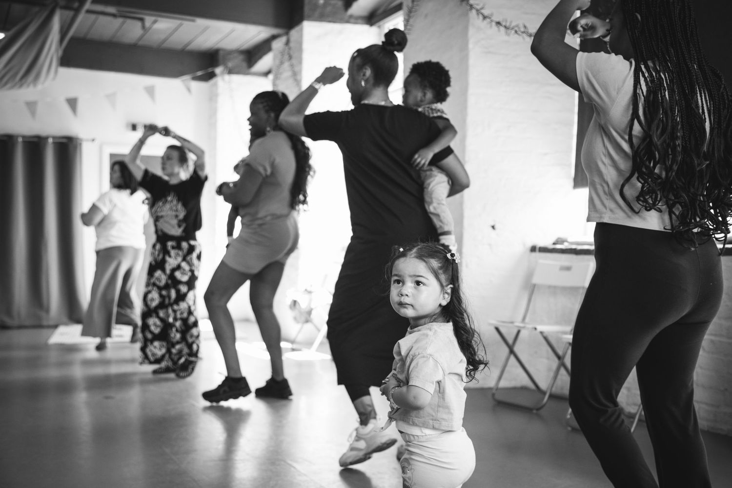 Black and white photo of group dancing and moving in studio space.